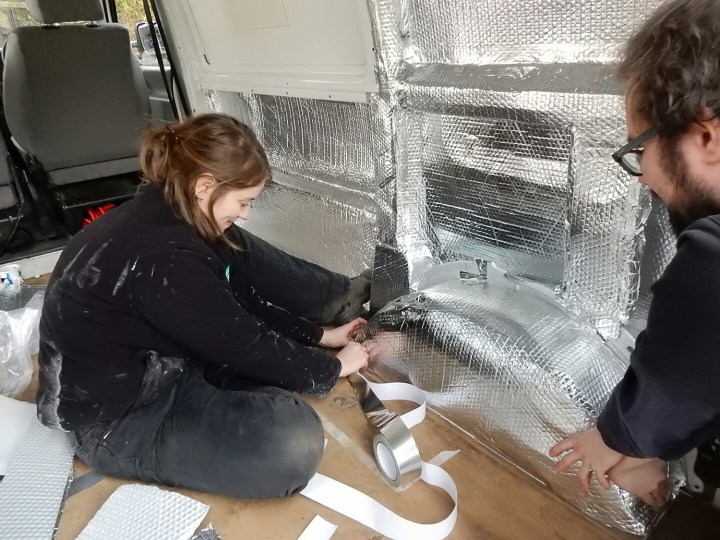 Taping insulation foil onto wheel arch