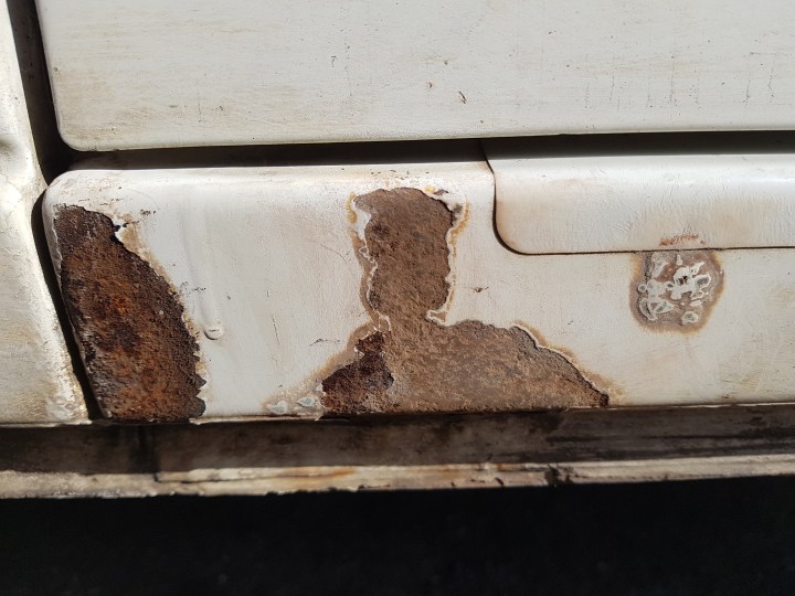 Breaking away cracked paintwork with rust underneath